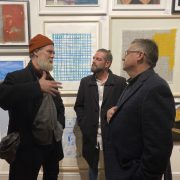 Three men discuss artworks