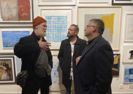 Three men discuss artworks
