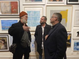 Three men discuss artworks