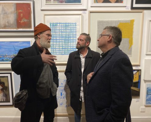 Three men discuss artworks